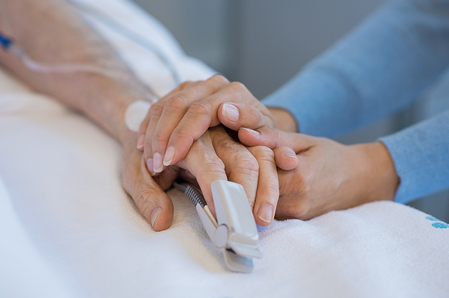 Daughter holding the hand of an elderly father. Closeup of woman holding senior man hand in hospital.
